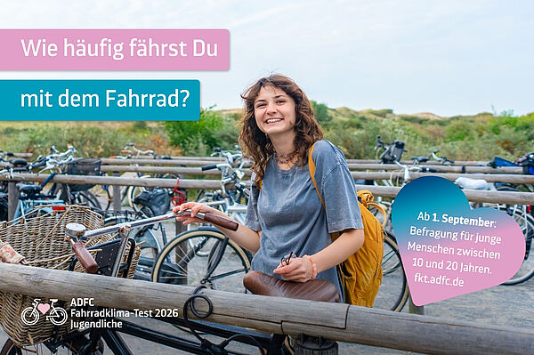 Eine junge Frau steht mit einem Fahrrad an einem Fahrradparkplatz. Im Hintergrund stehen viele weitere Fahrräder.